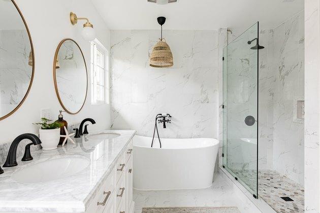 baie albă, blat de cuarț pe deșert alb, cadă mare de înmuiere albă, duș din sticlă, două oglinzi rotunde cu bordură aurie