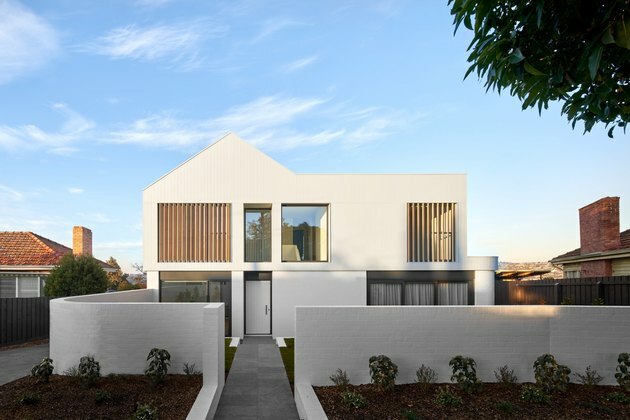 Exterior de casa contemporâneo branco com pranchas de madeira e características minimalistas