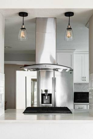 Cucina minimalista con armadi bianchi e lampadine a sospensione nere