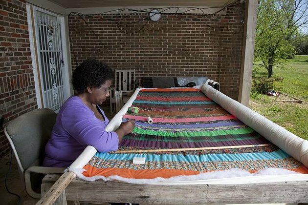 vrouw zit voor quilt ze werkt aan