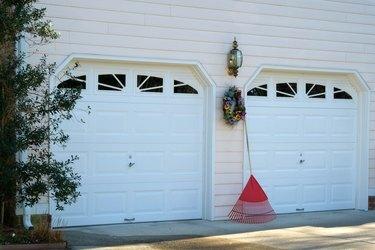 Grėblys ir vainikas tarp dviejų garažo durų