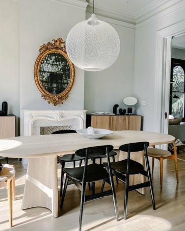 traditionele schoorsteenmantel decor in eetkamer met witte hanglamp en sierlijke gouden spiegel