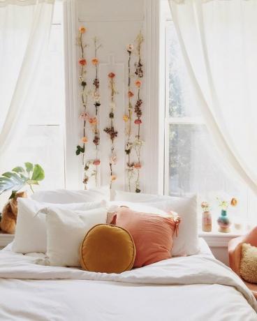 slaapkamer met gedroogde bloemen boven het bed