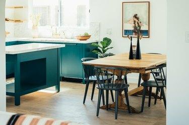 sinivihreä keittiö, jossa puupöytä ja mustat tuolit