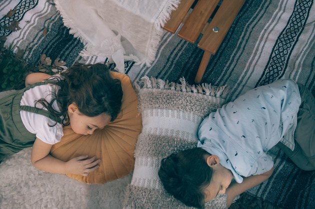 Du vaikai miegojo ant pagalvių apšvietimo vietoje