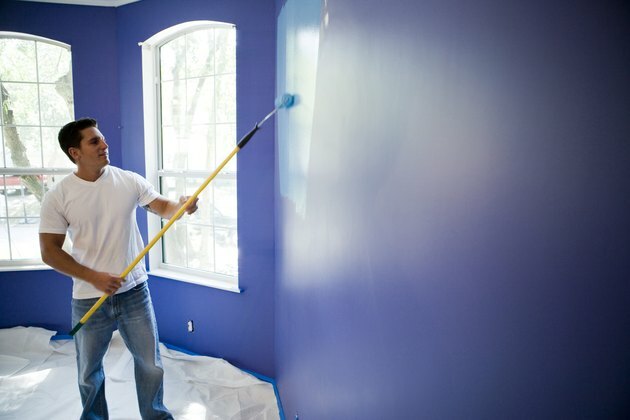 Ung mann som maler vegg med malerulle i hus