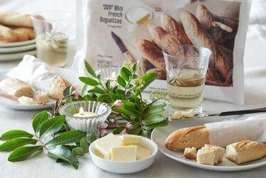 mesa com verduras e velas, manteiga e baguete