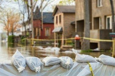 Sacos de arena de protección contra inundaciones con casas inundadas en el fondo