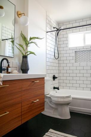 banheiro moderno de meados do século pequeno com vaso preto e branco e chuveiro com piso de metrô branco