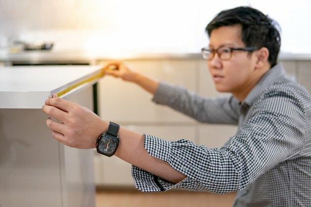 Un bărbat asiatic care folosește bandă de măsurare pe blatul de bucătărie