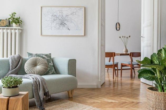 Sala de estar escandinava elegante com sofá moderno de design, móveis, maquete de mapa de pôster, plantas e acessórios pessoais elegantes. Decoração moderna. Espaço aberto com sala de jantar. Modelo pronto para uso.