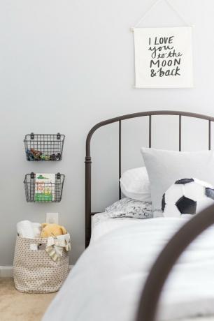 Organização do quarto infantil com cestos de arame na parede e estrado de metal