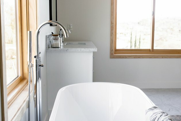 نوافذ الحمام المنزلقة في الحمام مع حوض استحمام أبيض وصنبور فضي