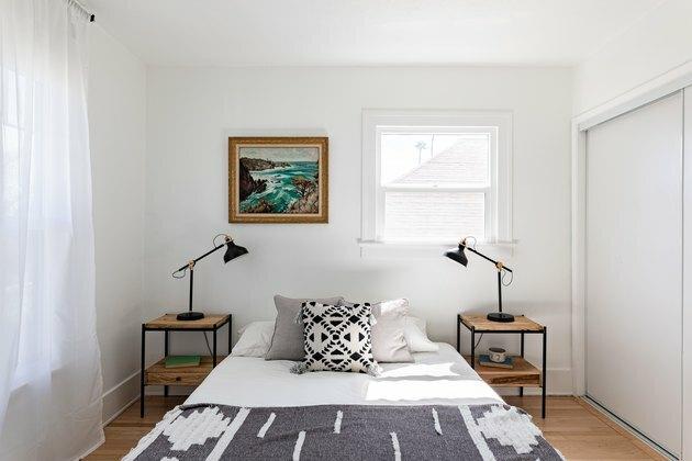 Quarto com almofada e cobertor boho, duas mesinhas laterais com lâmpadas pretas