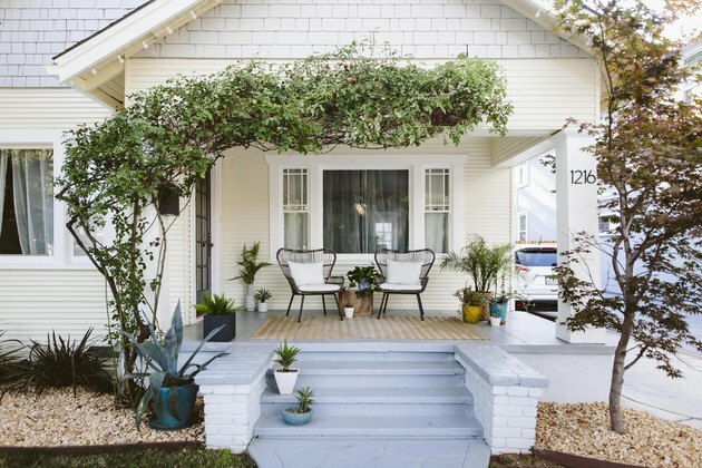 exterior da casa branca com degraus da varanda azul claro e vegetação