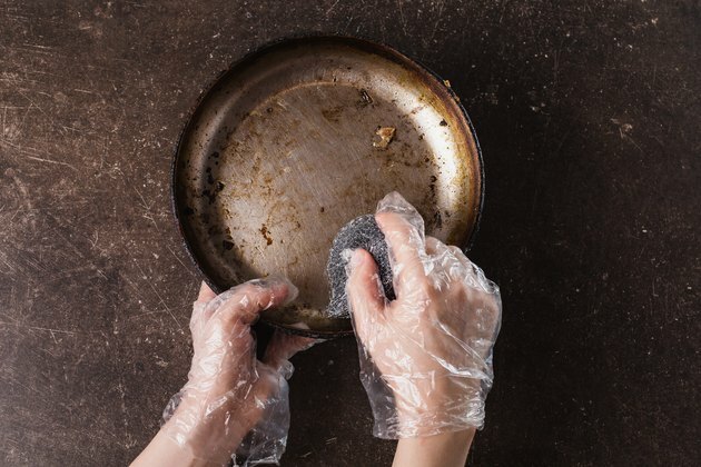 Lavare la padella su uno sfondo di marmo scuro. Igiene. Lavare i piatti con i guanti