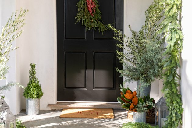 decorações de natal na porta da frente com brindes de porta vermelha e verde e folhagem fresca