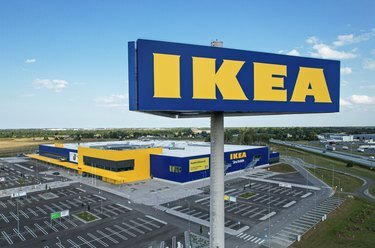 Un'insegna IKEA davanti a un negozio IKEA con un parcheggio vuoto.