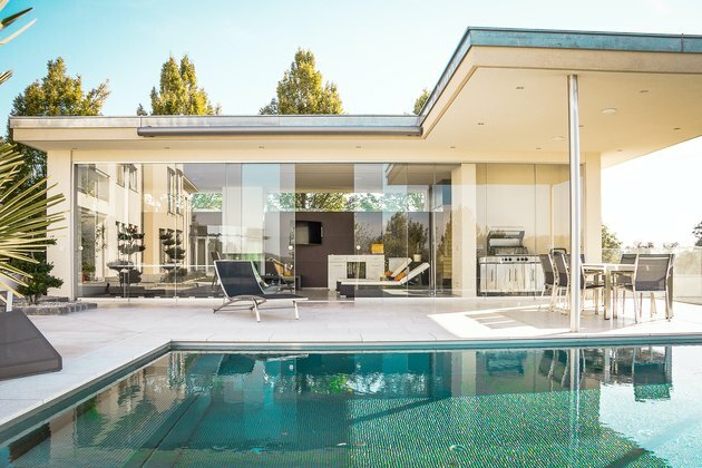 casa com paredes de vidro e piscina nas proximidades