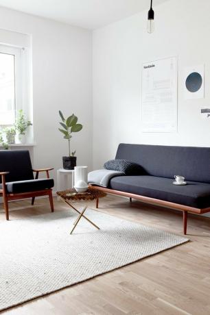 minimalistische verlichting in de woonkamer met donkergrijze futon en neutraal tapijt