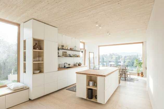 ilha de cozinha moderna com armários brancos e bancada de madeira