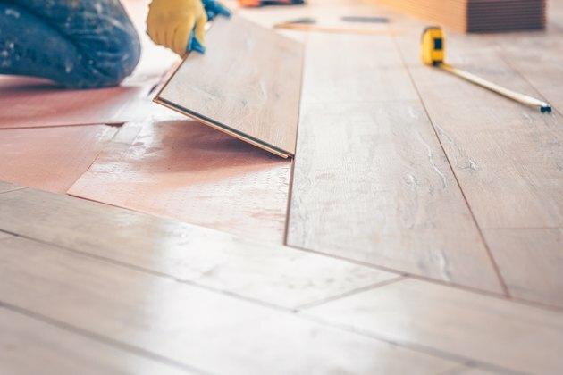 Pemasangan profesional penutup lantai, pekerja dengan cepat dan kualitatif memasang papan laminasi