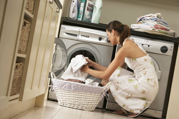 Moteris virtuvėje krauna skalbimo mašiną