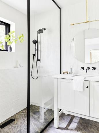 banheiro moderno branco com chuveiros pretos e acabamento preto ao redor da divisória de vidro e acessórios pretos