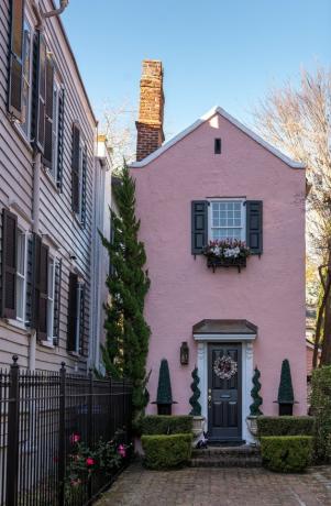 roze traditionele stucwerk huizen met vormsnoei en bakstenen loopbrug