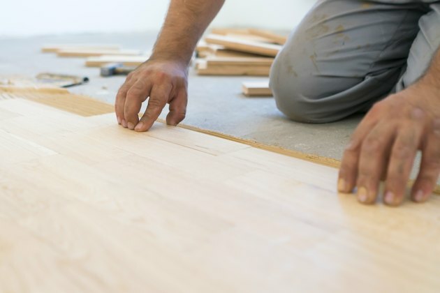 Carpintero alineando tablón laminado de parquet