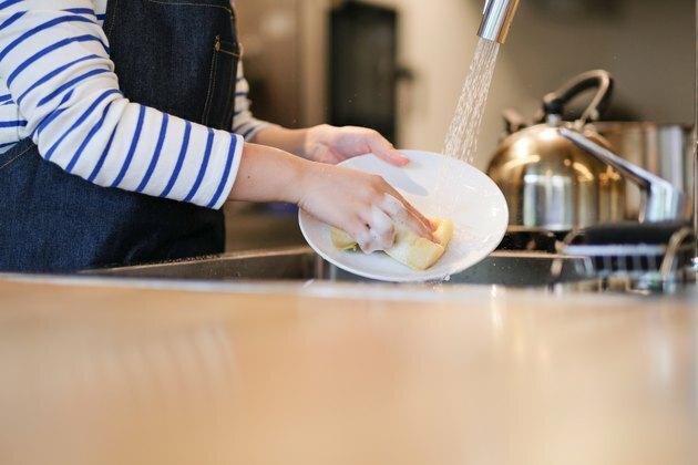 Garçonete lavar o prato na cozinha do restaurante