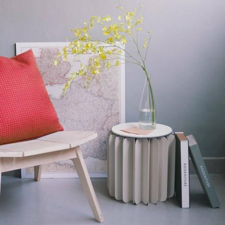 Mesa circular de papel dobrada com vaso em cima e livros encostados nela