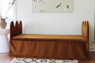 DIY bølget benk daybed med kobberfløyelsstoff med abstrakt kunstverk hengt over