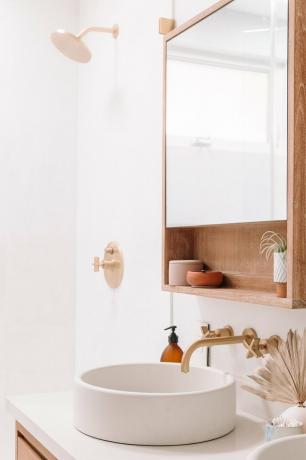 Torneira de banheiro de latão no banheiro boho com pia circular e torneiras de latão fixadas na parede