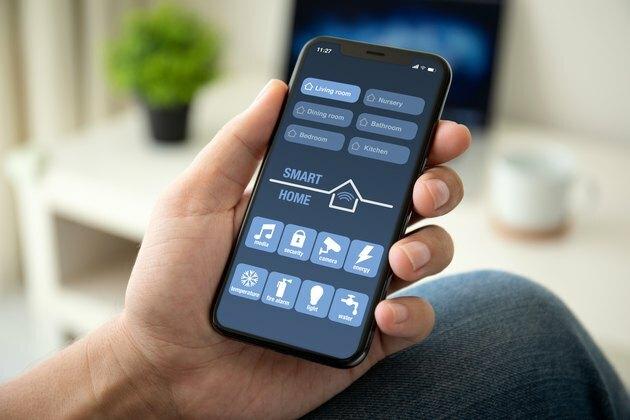 mand hånd holder telefon med app smart hjem i rummet