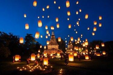 Lanternes célestes montant au-dessus d'un temple dans le ciel nocturne.