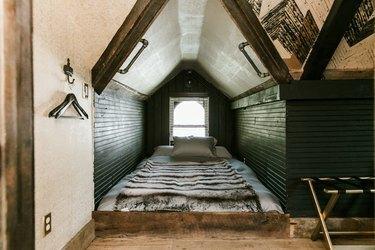 miegamasis kampelis žaliomis sienomis, lova ant grindų ir stačiai nuožulniomis lubomis