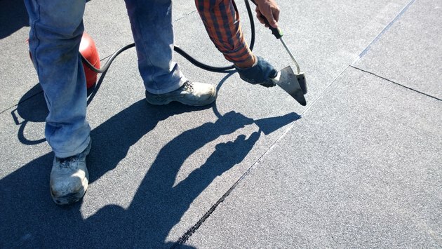 Çatı ustası bitüm çatı kaplama keçe rulo gaz ısıtıcı meşale alevi ile erime için hazırlanıyor