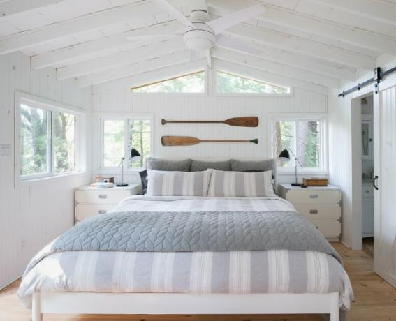 quarto costeiro caiado de branco com remos acima da cama