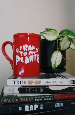 Caneca I Rap To My Plants em uma pilha de livros