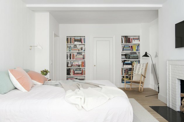 celadon kleuren op bedkussens in witte slaapkamer met open haard