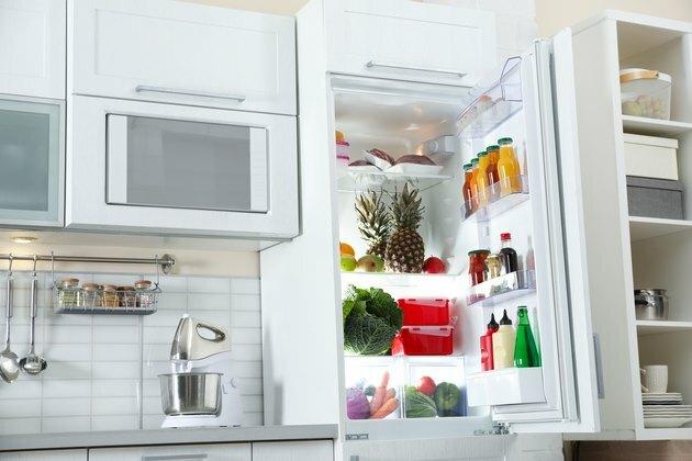 Abra el refrigerador lleno de productos en el elegante interior de la cocina