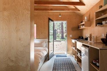 Eine Holzhütte im Wald mit einem minimalistischen Schlafzimmer und Holzwänden und Regalen