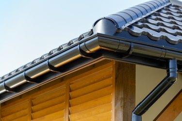 Naujo modernaus namo kampas su stogu ir lietvamzdžiu bei medinėmis langinėmis