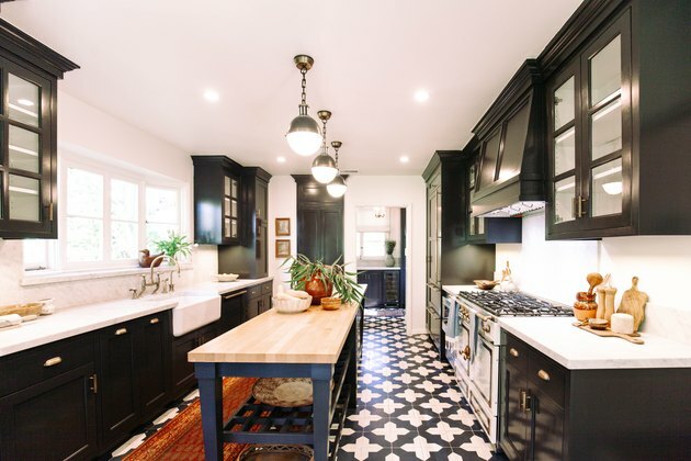 Cozinha com piso de cerâmica azul e branco, armários azul escuro, luzes suspensas e fogão vintage