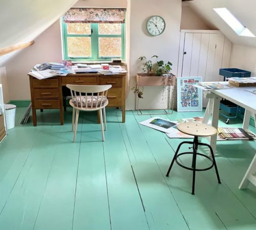 Escritório em casa para dois escritórios no sótão com piso de madeira pintada de turquesa, mesa vintage, banco, relógio de parede.