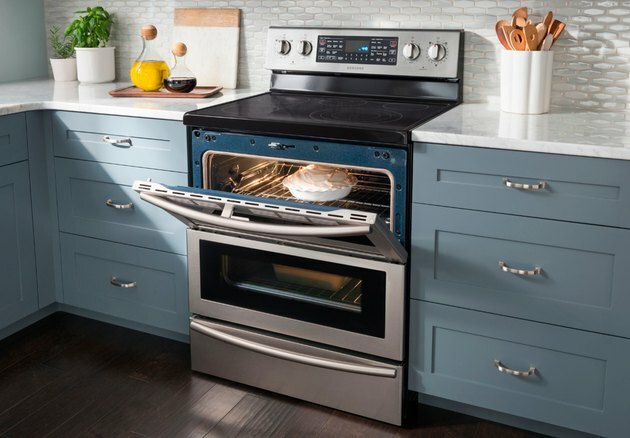 Fogão elétrico em cozinha azul com porta de forno aberta