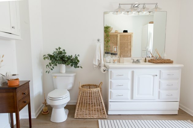 гледка към суетата на баня с единични мивки, огледало за баня, тоалетна и декоративни кошници