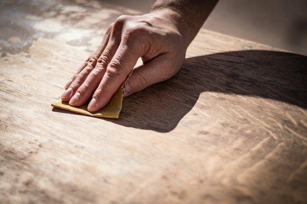 Grintosa mano dell'uomo stagionato levigatura di una superficie di legno