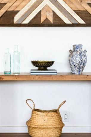 Idéias para decoração de parede de corredor com uma parede de madeira pendurada sobre uma prateleira de madeira com vasos e uma cesta de fibra